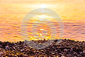 Golden pebbles on the seashore in the morning, at dawn, sea background