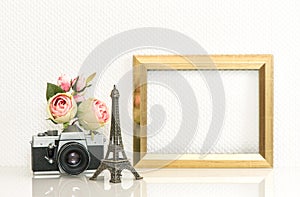 Golden picture frame, rose flowers and vintage camera. Paris tra