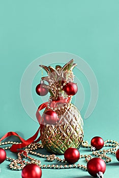 Golden pineapple decorated with red Christmas ball, ribbons and garlands