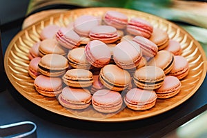 Golden plate of pink and orange macarons