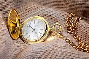 Golden pocket watch on fabric