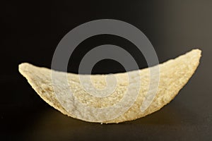 Golden potato chip on the black, selective focus, close-up