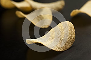 Golden potato chips on the black, selective focus, close-up