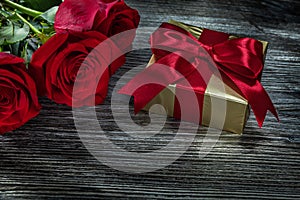 Golden present box red roses on wooden board