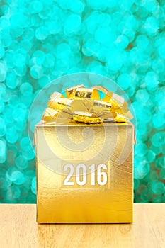 Golden Present box with 2016 word year at green bokeh light back