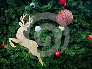 Golden Reindeer and Balls Decorated on Green Christmas Tree