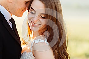 Golden rays of evening sun beautify pretty wedding couple