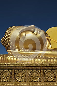 Golden reclining Buddha and Dhammajak blue sky Songkla