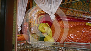 Golden reclining Buddha statue in vibrant Buddhist temple with elaborate murals, colorful decor, serene ambiance