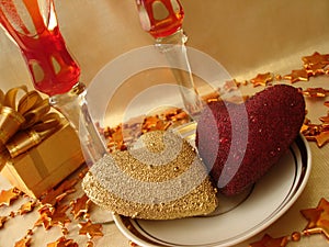 Golden and red hearts, gift box and glasses on celebratory table