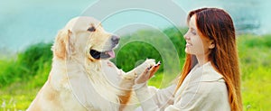 Golden Retriever dog giving paw to hand owner woman on grass training