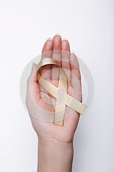 Golden ribbon in hand, symbol childhood cancer, peach uterine ca