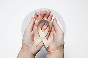 Golden ribbon in hands, symbol childhood cancer, peach uterine c