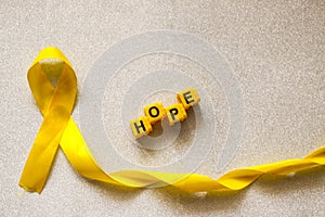 Golden ribbon and words made up of children`s plastic beeches. concept - a symbol of childhood cancer, pediatric oncology