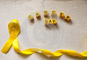 Golden ribbon and words made up of children`s plastic beeches. concept - a symbol of childhood cancer, pediatric oncology