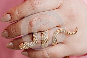 A golden ring in the hand of a woman in the form of a snake.