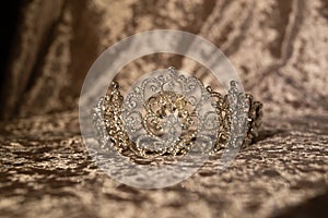 Golden royal crown on velvet fabric background. Jewellery