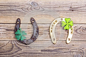 Golden and rusty horseshoes and clover leaves on old wooden boar