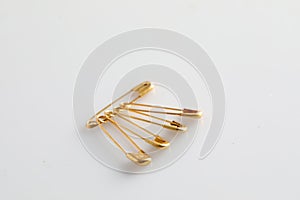 Golden safety pins on white background, space for text