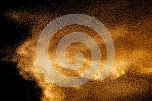 Golden sand explosion isolated on black background. Abstract sand cloud.Sandy fly wave in the air