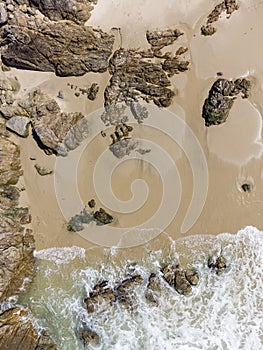 golden sand, rocks and a wave arriving