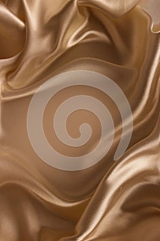 Golden satin background. Silk fabric with pleats.