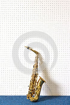 Golden saxophone on white and blue wall background