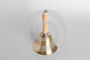 Golden school bell with wooden handle on grey background