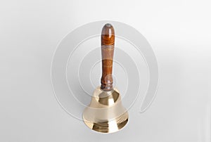 Golden school bell with wooden handle on grey background