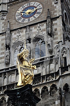 Golden scuplture of Virgin Mary at  clock tower Marienplatz under blue sky backgrounds, Munich, Germany, Travel