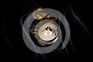 Golden shiny bitcoin lies on the dark material.