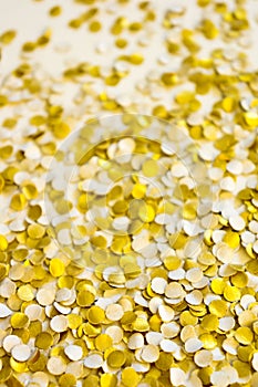 Golden shiny confetti on a white background.