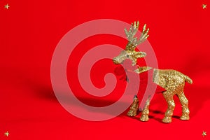 Golden  shiny reindeer figurine on a red fabric background. Christmas background card  gift card  red star - pendant tag