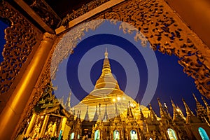 Golden Shwedagon Pagoda at night with twilight sky through the door frame