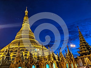 The golden Shwedagon Pagoda in Yangon formerly Rangoon is dramatically illuminated in front of the deep blue twilight sky, in