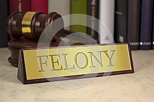 Golden sign with gavel and engraved word felony on a desk