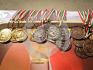 Golden, silver, bronze sports medal with red, white and green ribbon