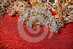 Golden and silver jewelry on red shiny glitter background