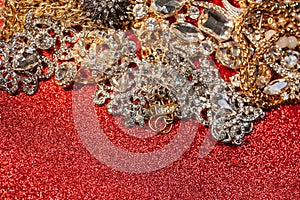 Golden and silver jewelry on red shiny glitter background