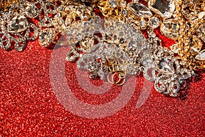 Golden and silver jewelry on red shiny glitter background