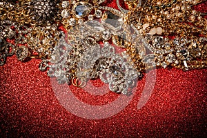 Golden and silver jewelry on red shiny glitter background