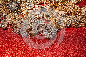 Golden and silver jewelry on red shiny glitter background