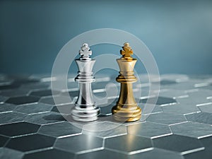 Golden and silver king, luxury chess pieces standing together on a silver hexagon pattern chessboard on blue background.