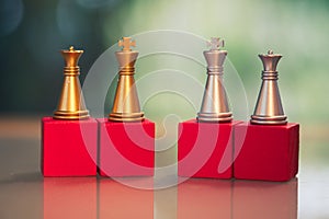 The golden and silver king and queen chess pieces on red wood block. Difference concept