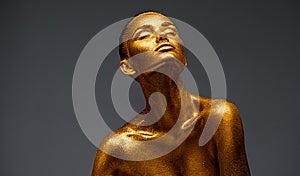 Golden skin beauty woman portrait. Fashion girl with holiday golden makeup. Body art