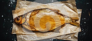 Golden smoked river bream on dark background, top view