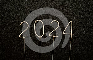Golden sparklers in the form of the numbers 2024 on a black background