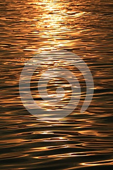 Golden sparkling morning sunlight reflections on the sea water surface with gentle ripples