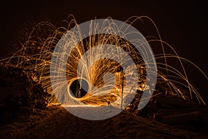 Golden sparks fly at night in winter snow through glowing steel wool spun in a circle, Germany