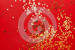 Golden stars confetti on red background. Christmas festive background